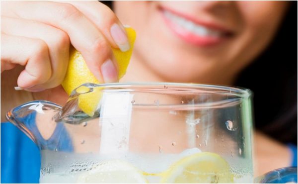 Девушка добавляет сок лимона в воду