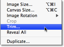 Select the Trim command from the Image menu in Photoshop.