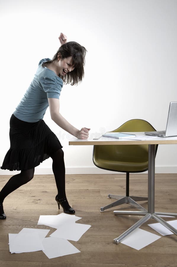 Angry Young Businesswoman Banging At Desk. Full length of angry young businesswoman banging at desk royalty free stock photos