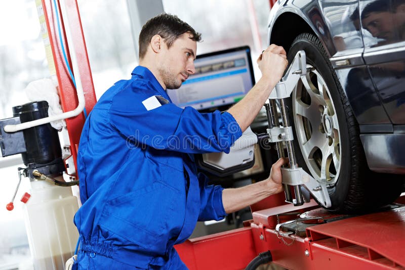 Auto mechanic at wheel alignment work with spanner royalty free stock photography