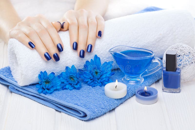 Beautiful blue manicure with chrysanthemum and towel on the white wooden table. spa royalty free stock photos