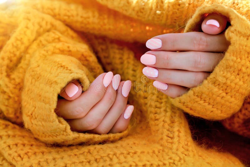 Beautiful female shaped pink manicure in an orange sweater. Pink caramel nails, gel polish royalty free stock images