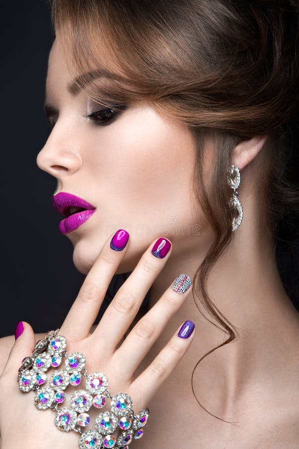 Beautiful girl with a bright evening make-up and purple manicure with rhinestones. Nail design. Beauty face. stock photo