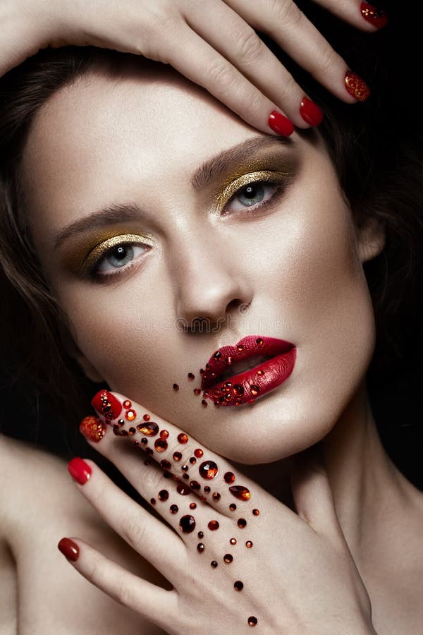 Beautiful girl with evening make-up, red lips in rhinestones and design manicure nails. beauty face. royalty free stock photo
