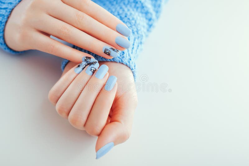 Beautiful New Year manicure. Blue nails with black design and rhinestones. Space stock photography