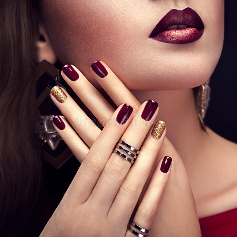 Beautiful woman with perfect make-up and burgundy and golden manicure wearing jewellery stock photography