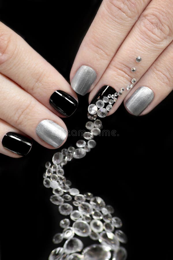 Black silver manicure on short nails with a design of a scattering of rhinestones of different shapes royalty free stock photo