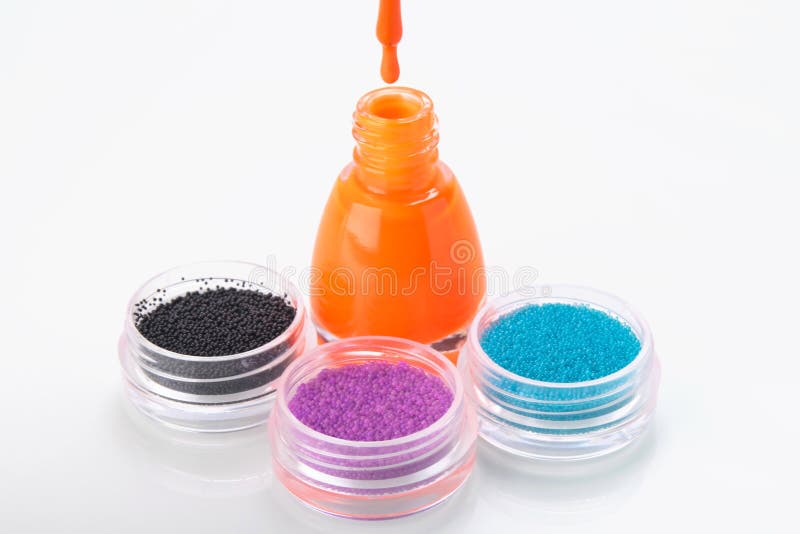 Bottle with nail Polish, surrounded by three containers of rhinestones, bouillon for manicure stock photos