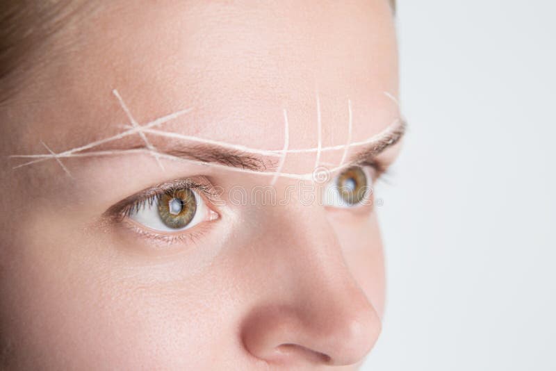 Brow marking and measuring before microblading or henna tattoo close-up. White brow paste, threading.  stock photo