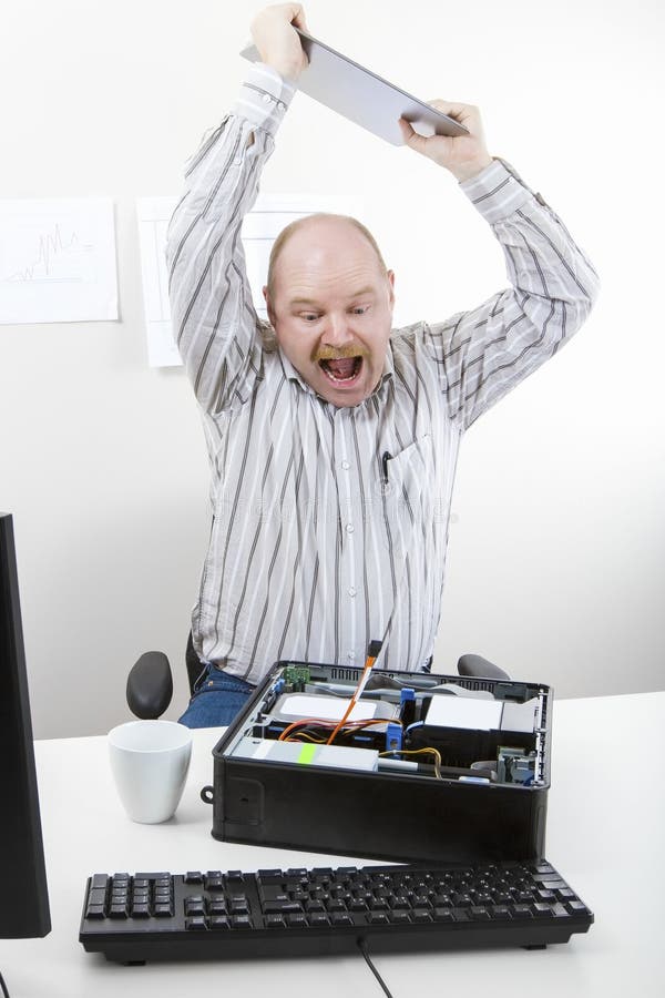 Businessman Banging File On Computer Chassis At Table. Furious mature businessman banging file on computer chassis at table in office stock photos