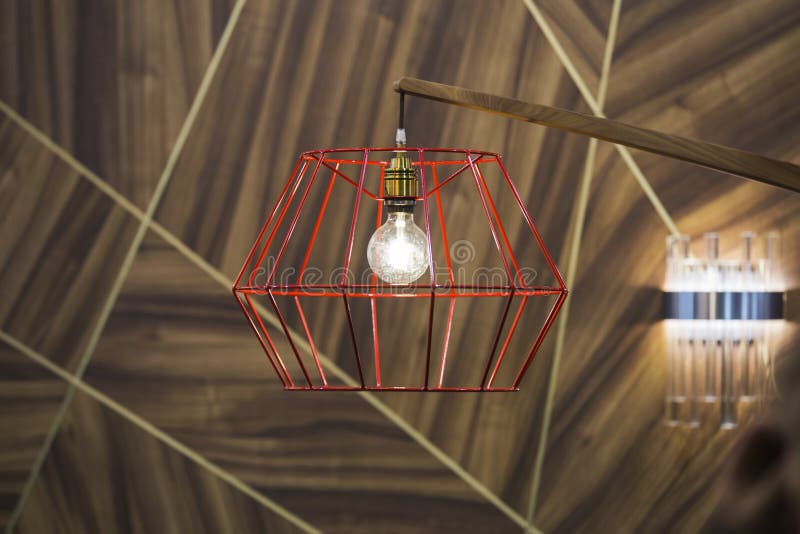 Close-up of a modern, red color copper lamp with bulb on wooden background.  royalty free stock photography