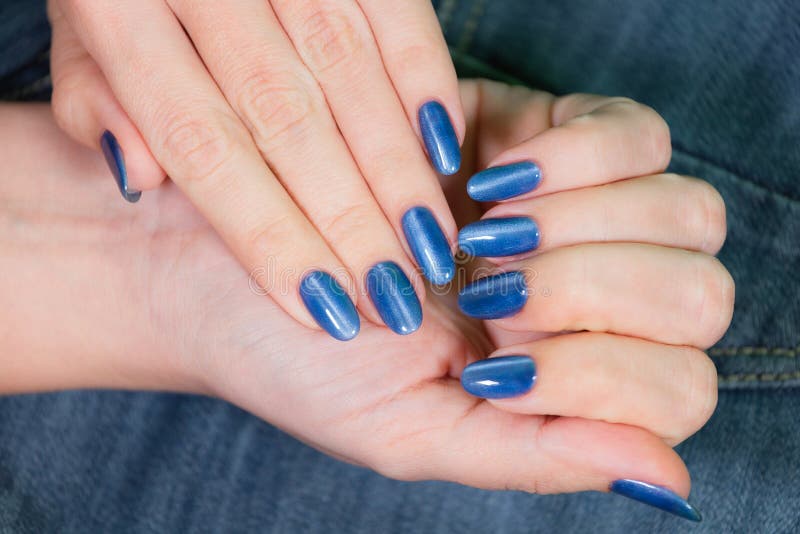 Female hands with blue glossy professional manicure stock image