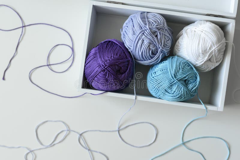 Colorful knitting balls in a white wooden box on the table with strands around. Colorful knitting balls in a white wooden box on the table with a lot of strands royalty free stock image