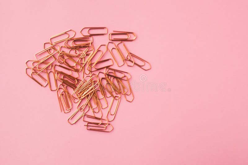 Copper color paper clips on a pink background. selective focus.  stock photo