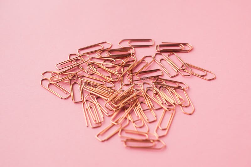 Copper color paper clips on a pink background. selective focus.  royalty free stock image