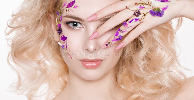 Cosmetics and manicure. Close-up portrait of attractive woman with dry flowers on her face, pastel color of nail design stock photography