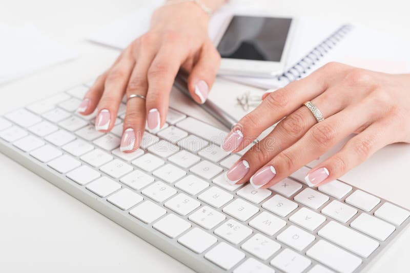Young businesswoman with beautiful manicure typing on keyboard at workplace royalty free stock photography