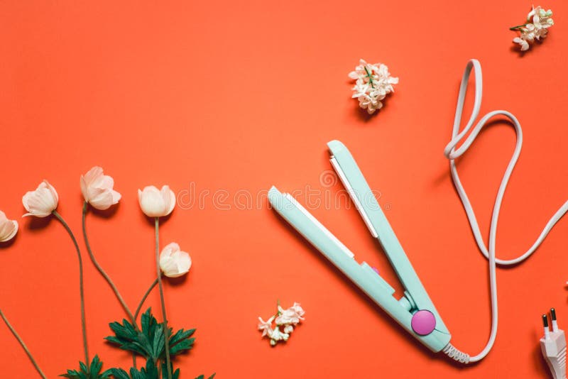 Curling iron ripple on a coral background. Hair accessory on orange background with flowers. Hairstyle tool.  royalty free stock image