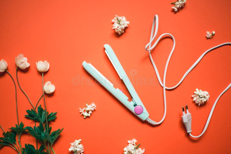 Curling iron ripple on a coral background. Hair accessory on orange background with flowers. Hairstyle tool.  royalty free stock photography