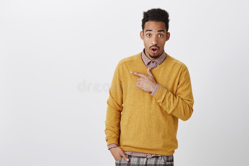 Discussing with friend shocking gossip about classmate. Attractive african-american male student with afro hairstyle in. Yellow pullover, dropping jaw from stock photography