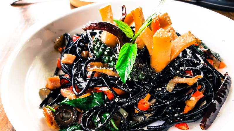 Drunken spaghetti strands Black on white plate. With sausage, chilies, basil royalty free stock photo