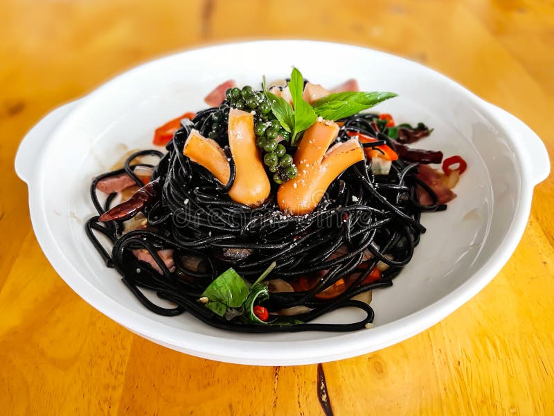 Drunken spaghetti strands Black on white plate. With sausage, chilies, basil royalty free stock images