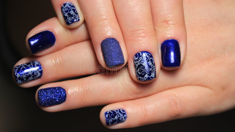 Evening manicure, design cold colors, blue gel polish with silver ribbons and pattern stock photo