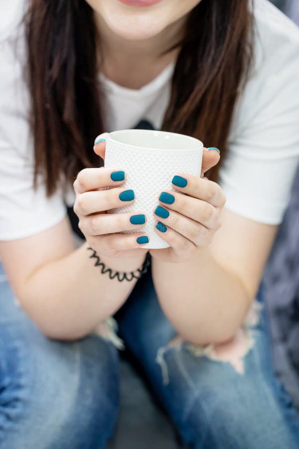 Female hands holding white cup. Manicure with deep turquoise blue nail polish royalty free stock photo