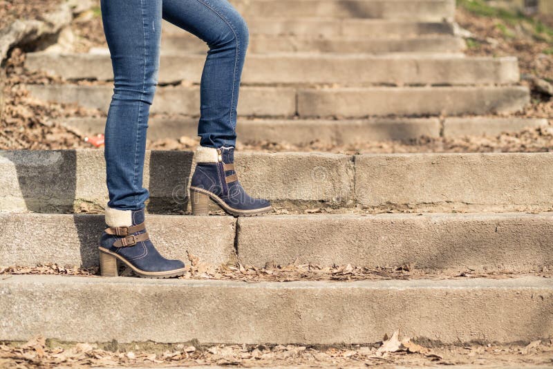 Female legs in winter boots and jeans on stairs. Female legs in winter boots and blue jeans on stairs. Fashion background stock photography