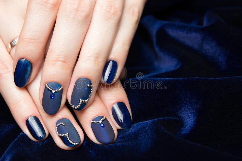 French manicure - beautiful manicured female hands with blue manicure with rhinestones on dark blue background royalty free stock images