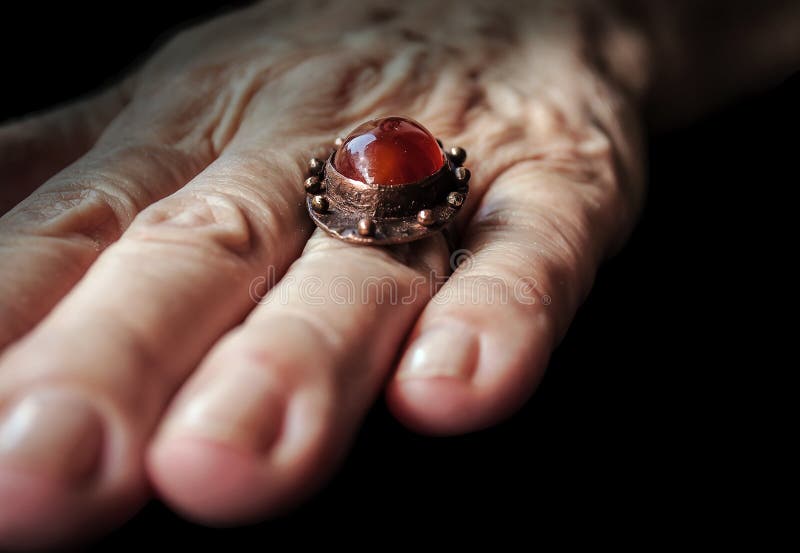 Gemstone Amber color ring with copper on older lady hand. This artistic ring is handmade by one artist in Serbia Southeast of Europe stock images