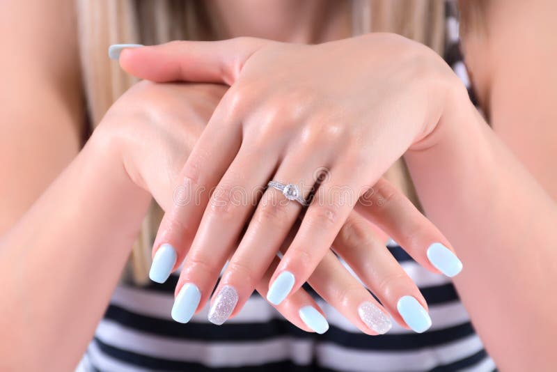 Girl hands with blue nails polish manicure and diamond engagement wedding rings royalty free stock images