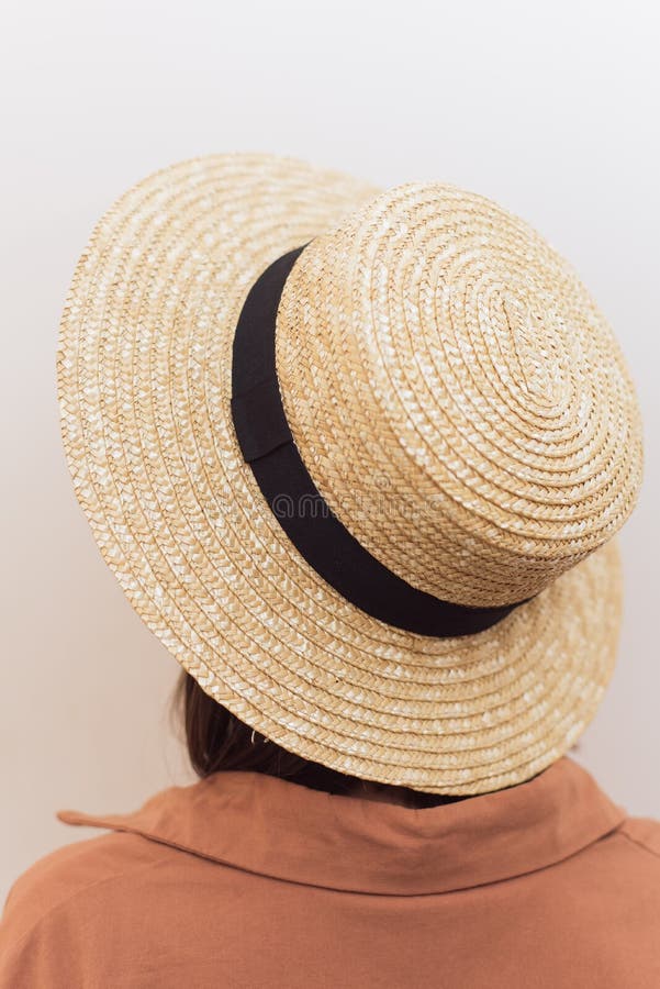 Girl with a square in a straw hat on a white background. The girl turned away from the camera, without a face. A beautiful hat on a girl in an orange shirt stock photography