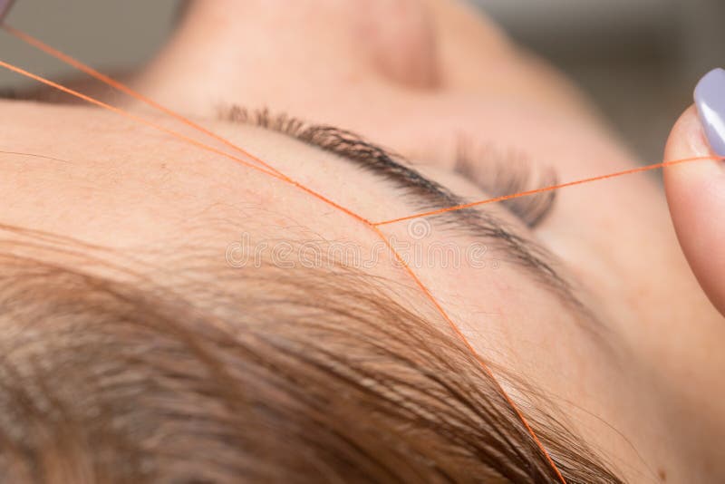 Grooming the eyebrows thread in a beauty salon stock photos