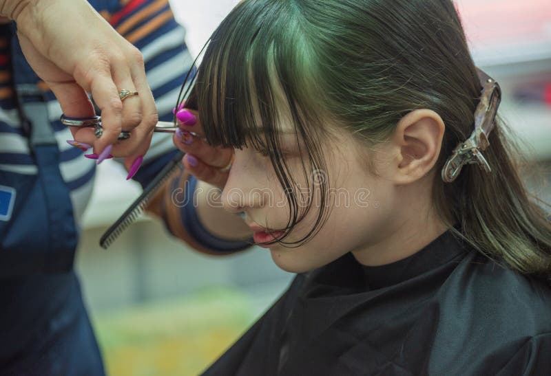 Hair salon concept. Girl bang bang in a beauty salon. A child in the barber cuts his hair royalty free stock photo