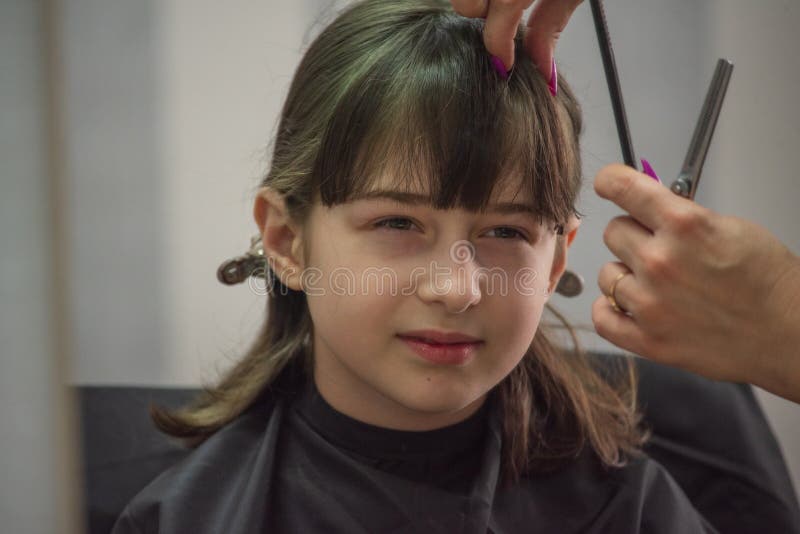 Hair salon concept. Girl bang bang in a beauty salon. A child in the barber cuts his hair royalty free stock photos
