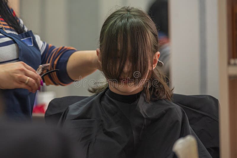 Hair salon concept. Girl bang bang in a beauty salon. A child in the barber cuts his hair stock image
