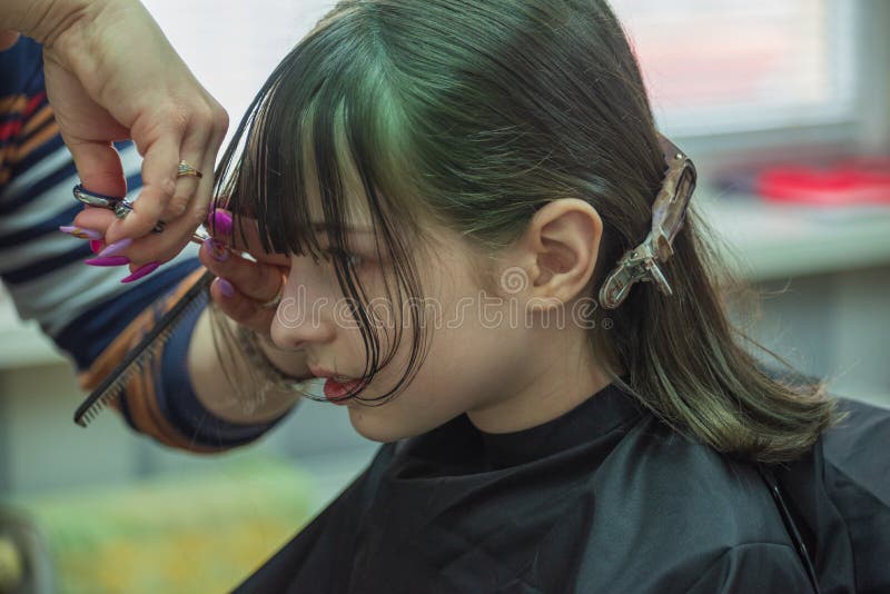 Hair salon concept. Girl bang bang in a beauty salon. A child in the barber cuts his hair stock photography