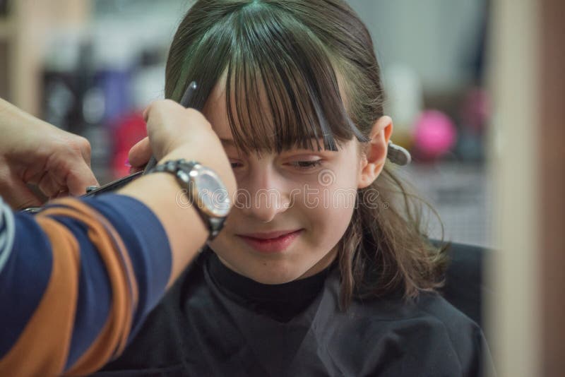 Hair salon concept. Girl bang bang in a beauty salon. A child in the barber cuts his hair stock photo