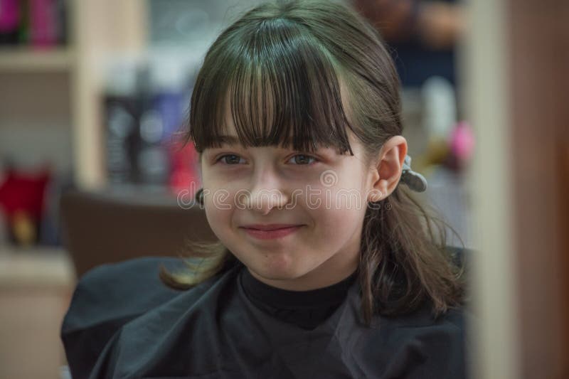 Hair salon concept. Girl bang bang in a beauty salon. A child in the barber cuts his hair royalty free stock photography