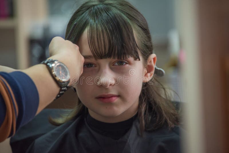 Hair salon concept. Girl bang bang in a beauty salon. A child in the barber cuts his hair royalty free stock image