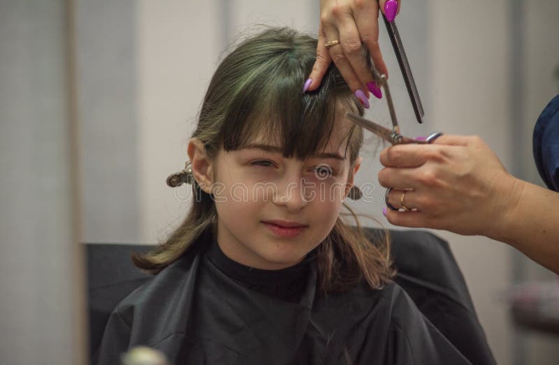 Hair salon concept. Girl bang bang in a beauty salon. A child in the barber cuts his hair royalty free stock photo