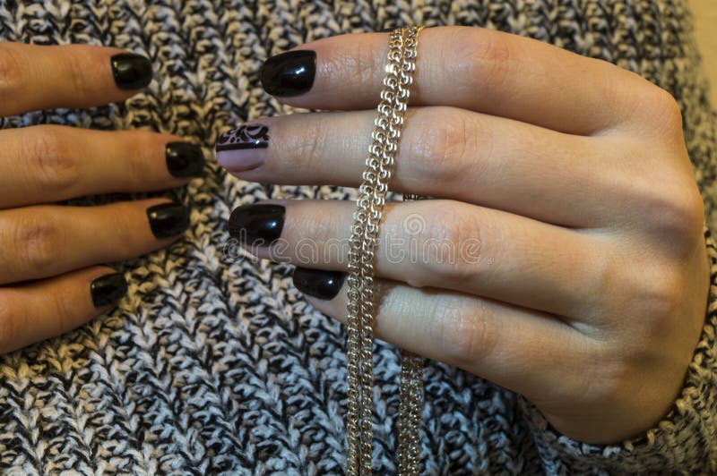 Girl`s hand with a beautiful manicure showing a chain with a cross stock photography