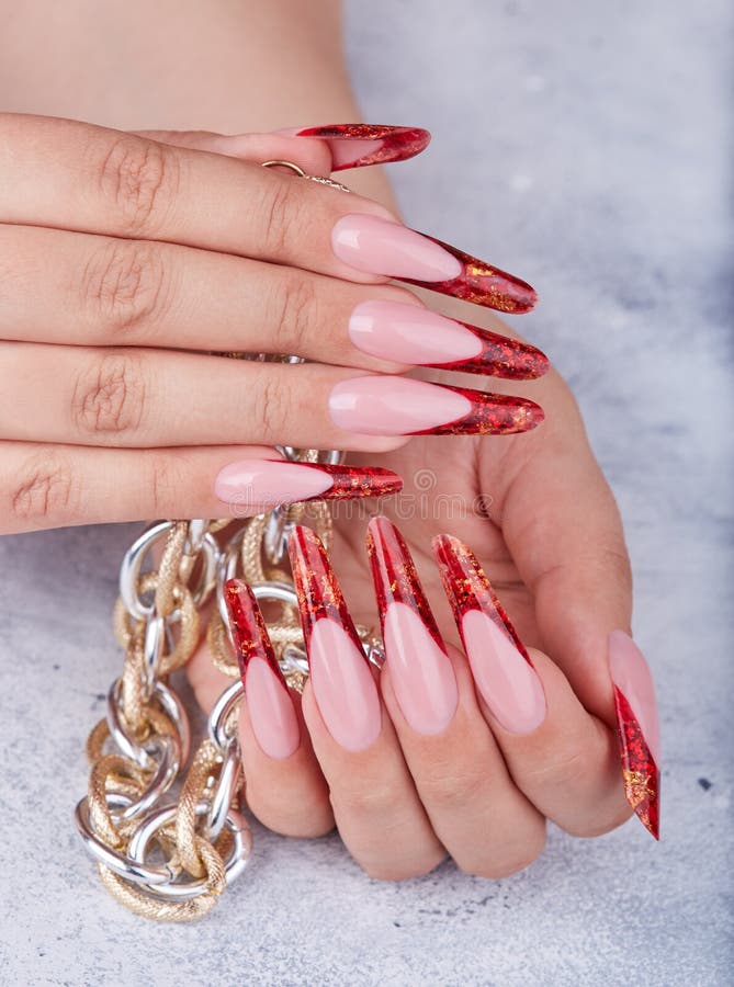 Hands with long red artificial french manicured nails holding a chain necklace stock photography