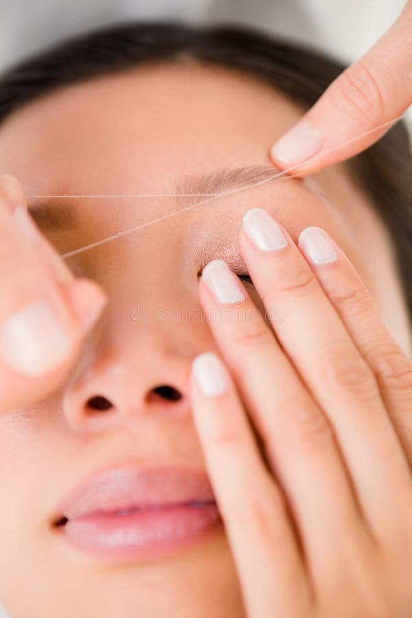 Hands threading beautiful womans eyebrow. Close up view of hands threading beautiful womans eyebrow royalty free stock photo