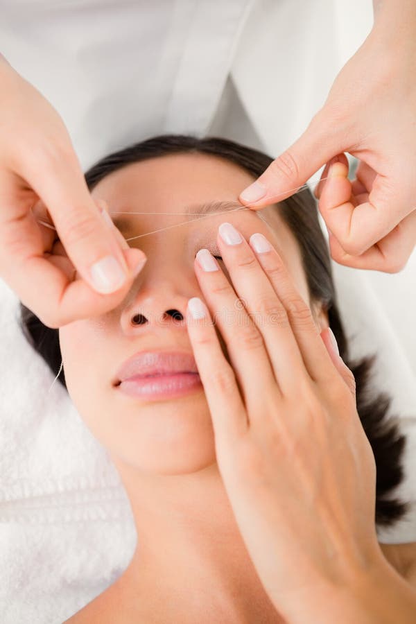 Hands threading beautiful womans eyebrow. Close up view of hands threading beautiful womans eyebrow royalty free stock photo