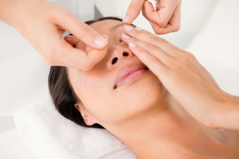 Hands threading beautiful womans eyebrow. Close up view of hands threading beautiful womans eyebrow stock image