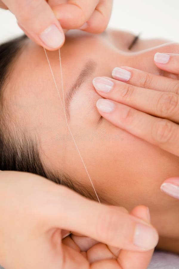 Hands threading beautiful womans eyebrow. Close up view of hands threading beautiful womans eyebrow royalty free stock photography