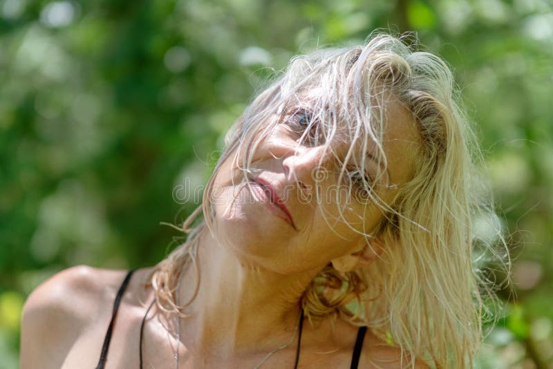 Happy middle aged woman with wet hair smiling in the forest. Happy middle aged woman with wet hair smiling at the lake in the forest stock image