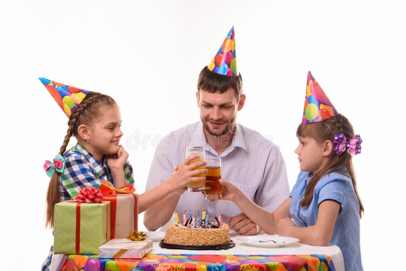 Kids and dad joyfully banging glasses of juice at a birthday party. Kids and dad joyfully banging glasses of juice at a birthday  party stock images